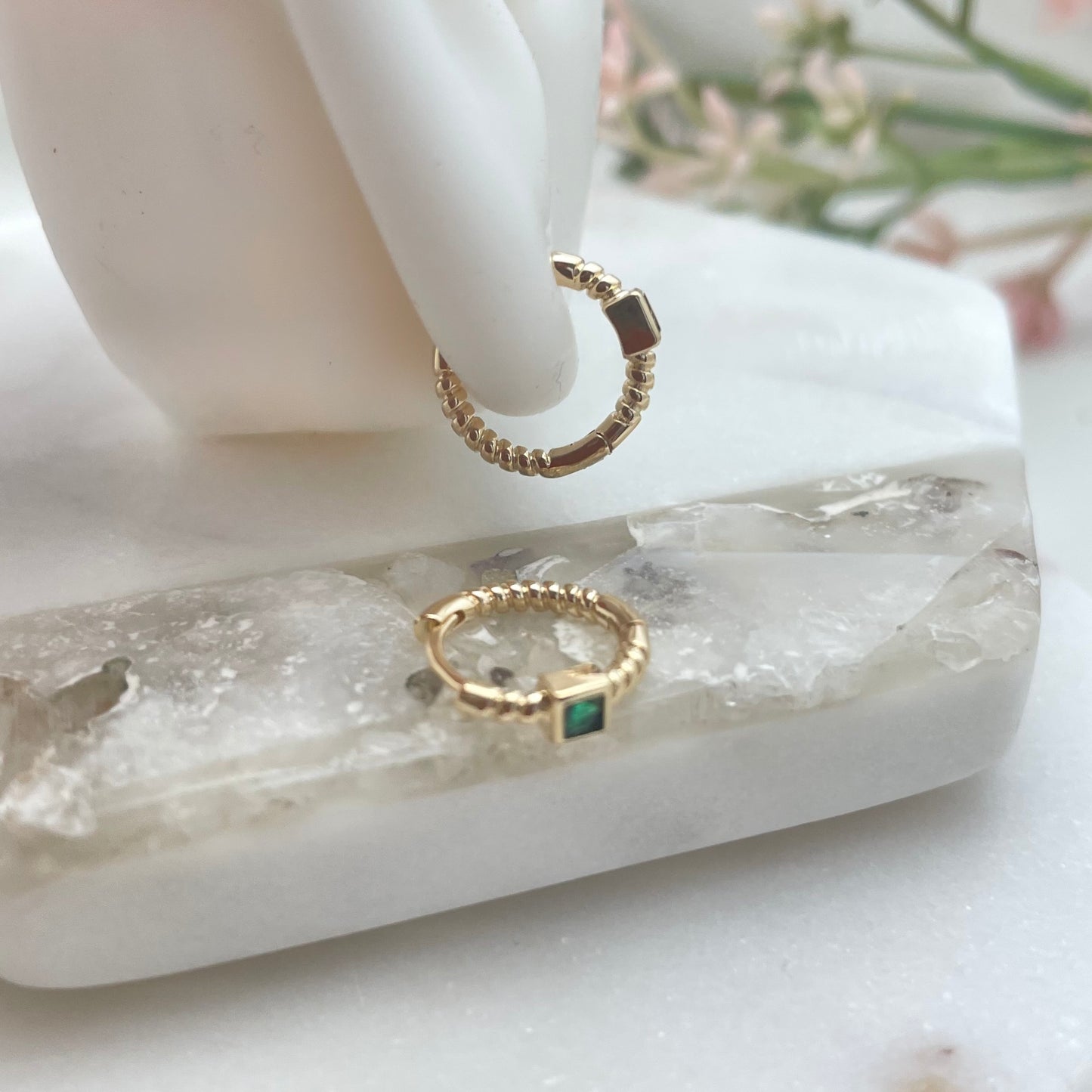 Close look on silicone ear of huggie hoop green crystal earrings