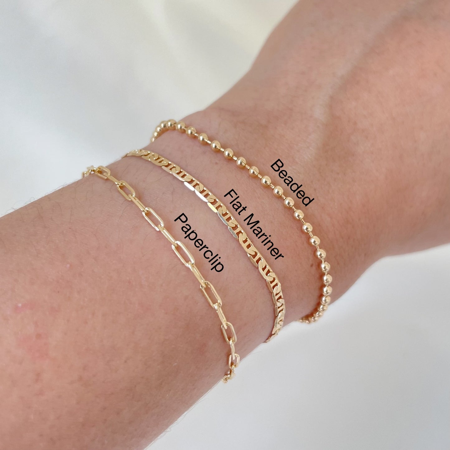 Gold bracelets on a wrist with labels indicating their styles.