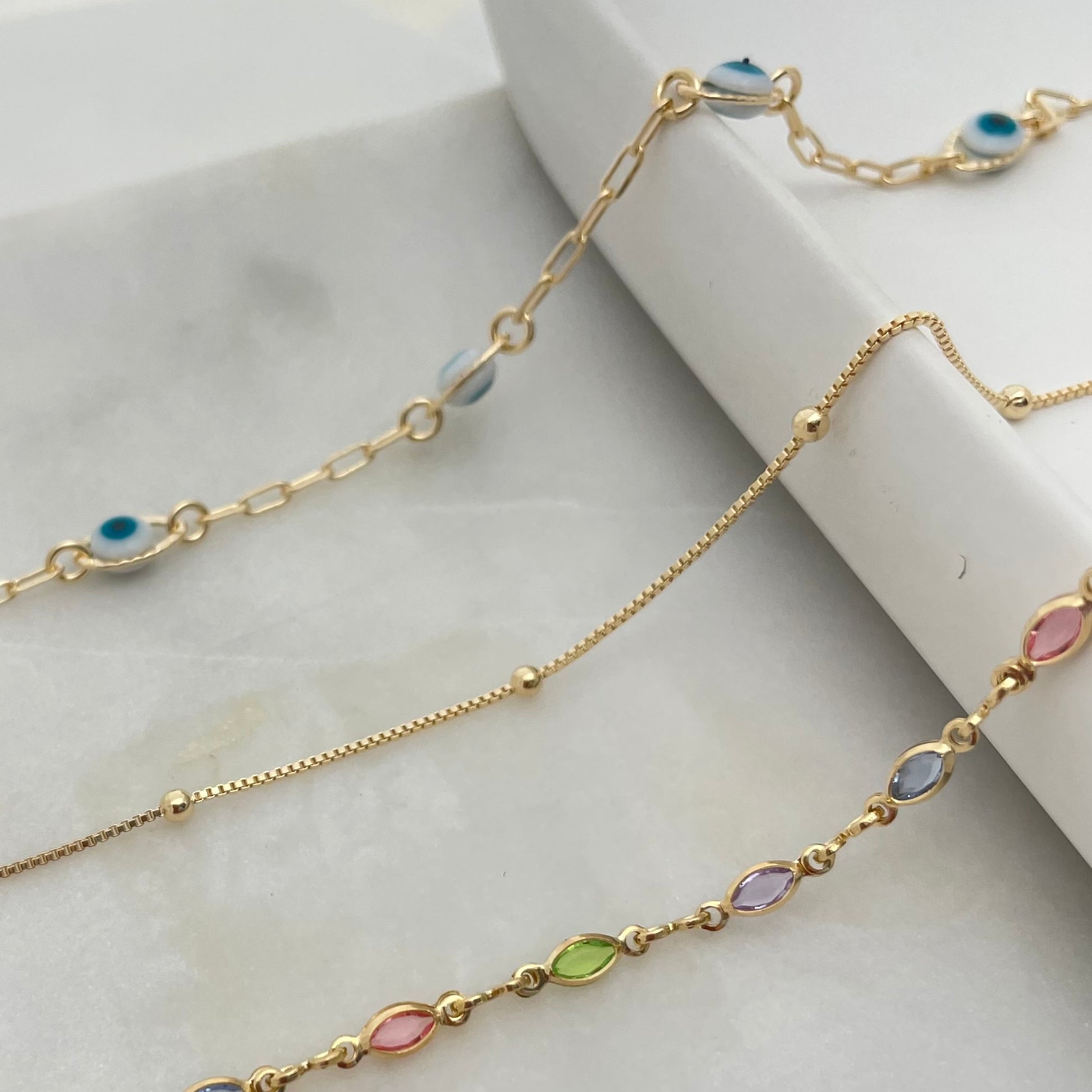 3 styles of anklet bracelets in 18k gold filled, featuring evil eye anklet, satellite anklet and colorful anklet bracelet. 