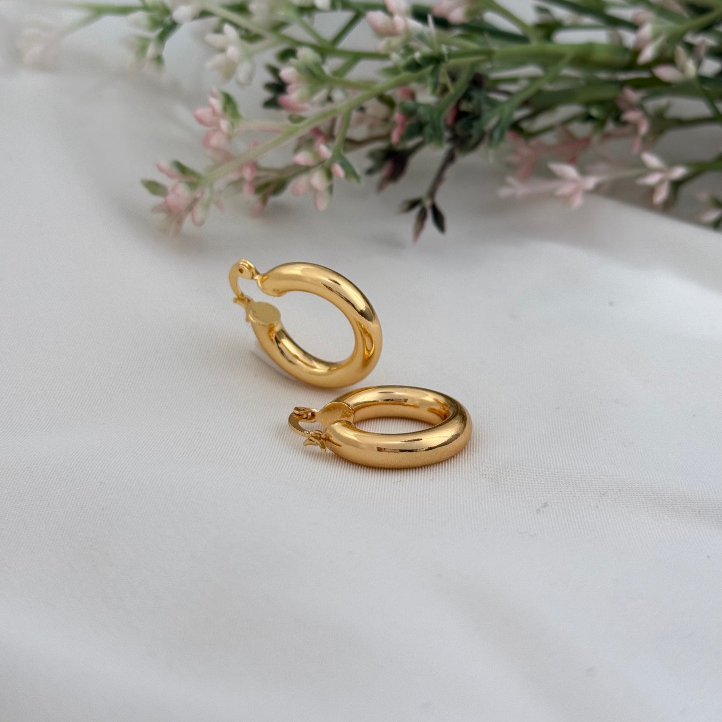 Gold hoop earrings on a white surface