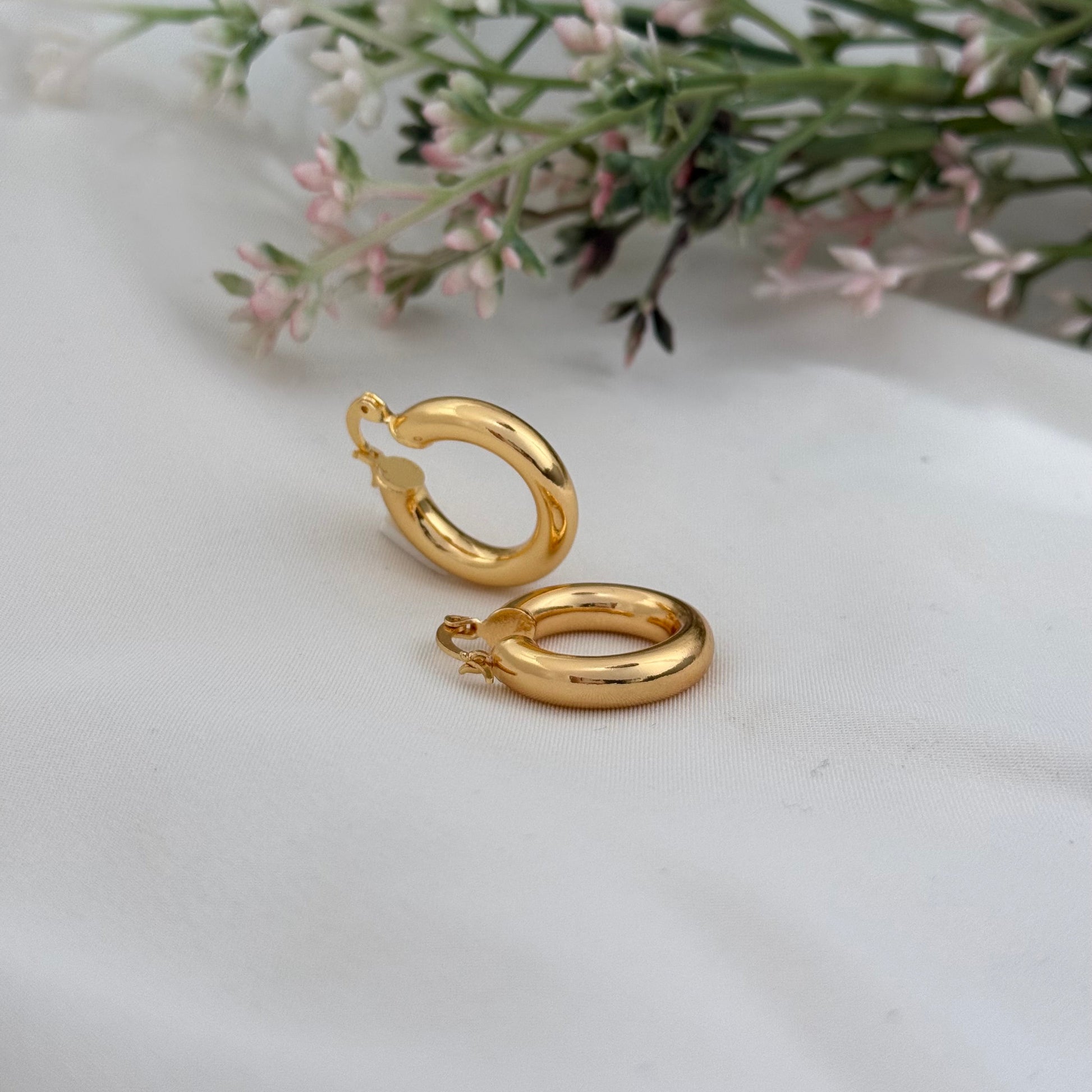 Gold hoop earrings on a white surface