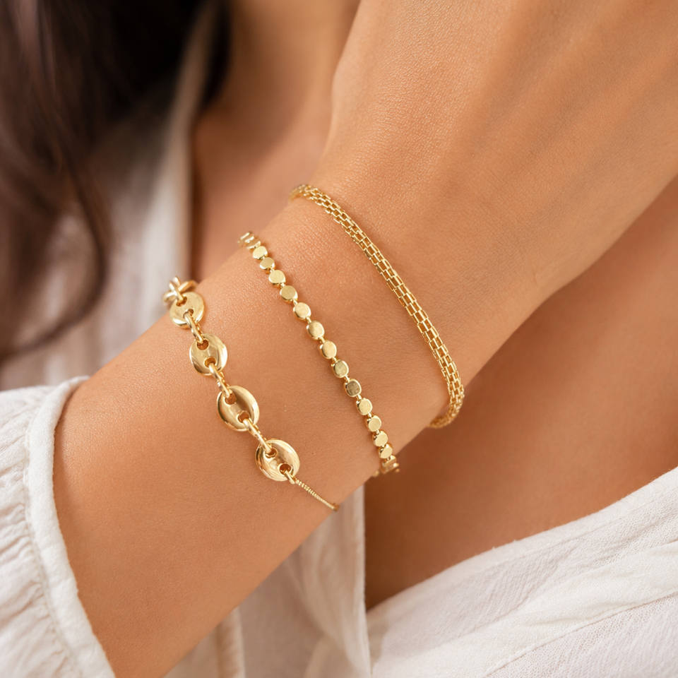 Gold bracelets on a person's wrist with a blurred background