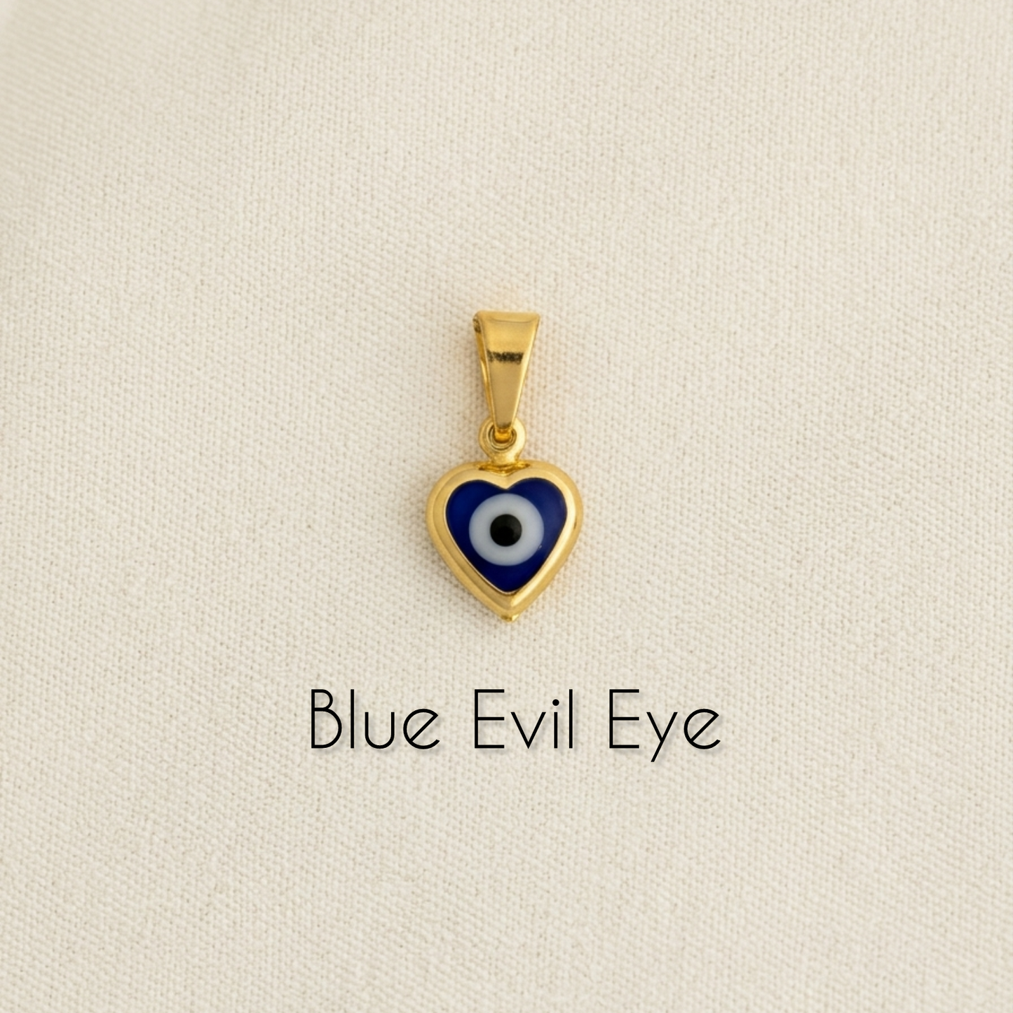 Gold filled heart-shaped blue evil eye pendant on a beige background