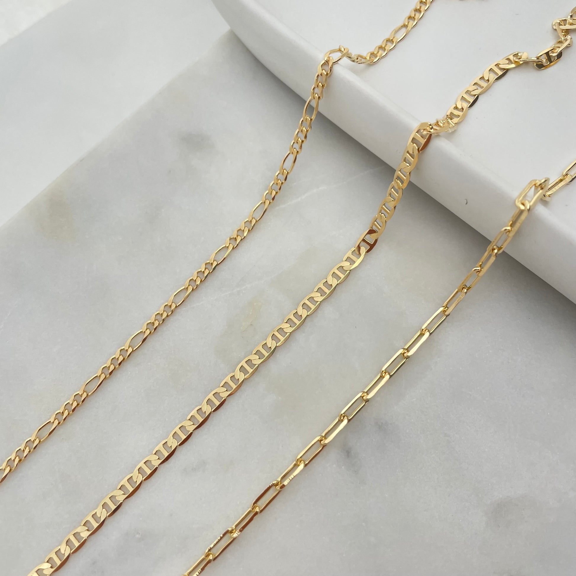 Close up of a 3mm gold filled set of anklets, paperclip, figaro and flat marine. 
