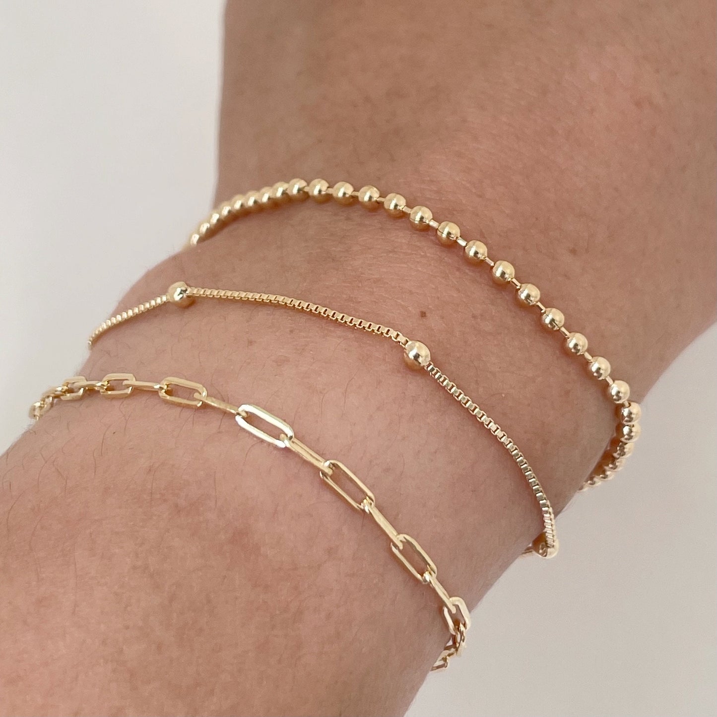 Close up of Set of 3 dainty bracelets, paperclip, satellite and beaded bracelet all in 18k gold filled