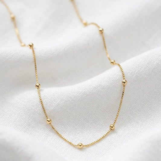 Gold necklace on a white fabric background