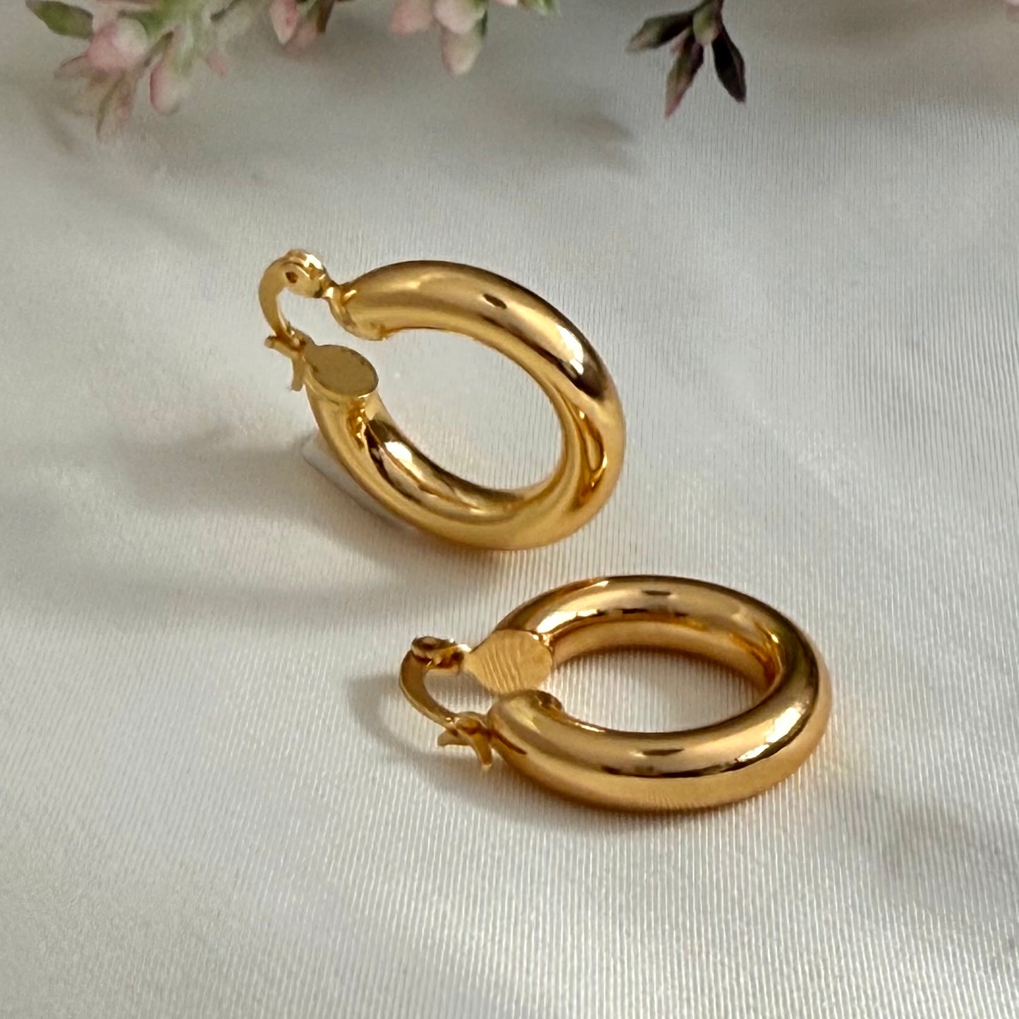 Gold hoop earrings on a light background