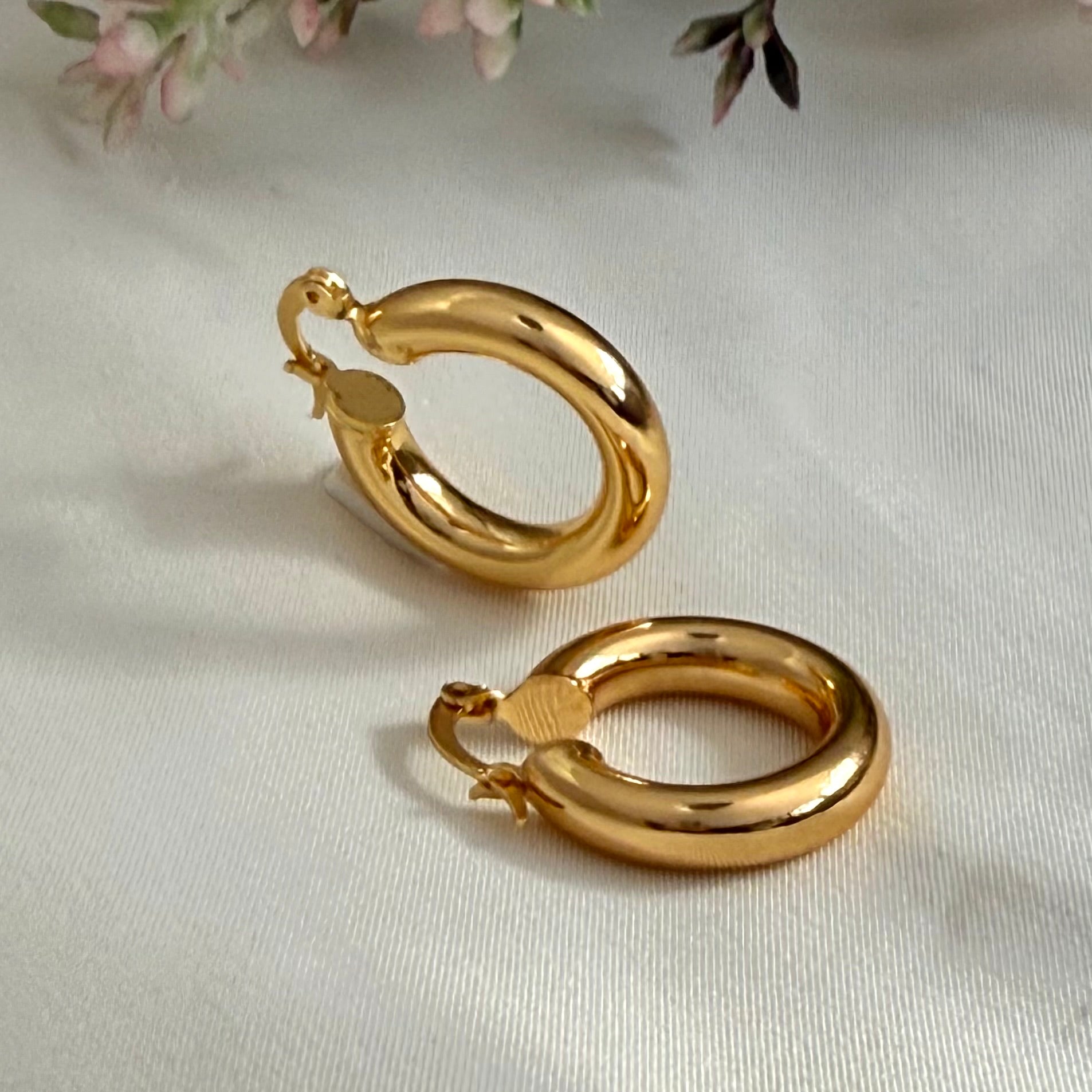 Gold hoop earrings on a light background