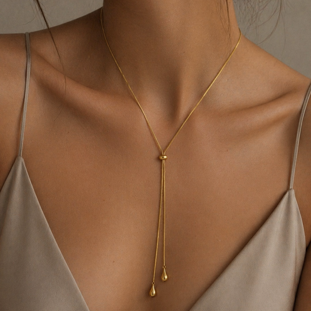 Gold adjustable necklace worn by a model in a beige top.
