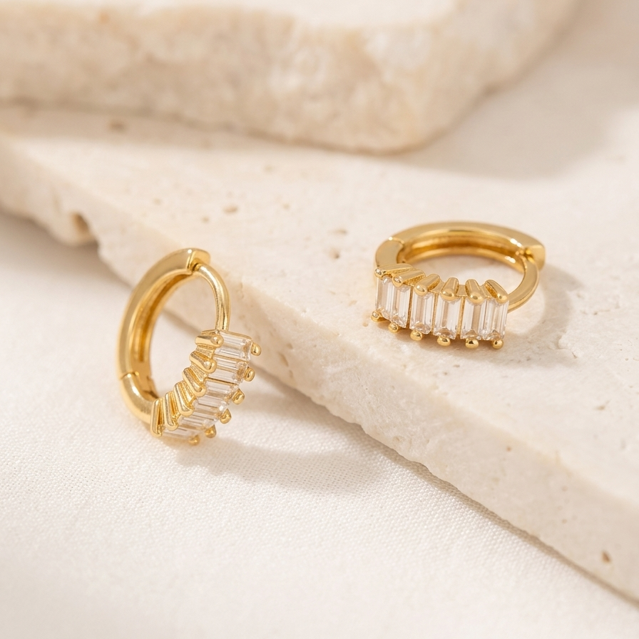 Gold filled baguette Crystal huggie Hoops earrings over cream stone.