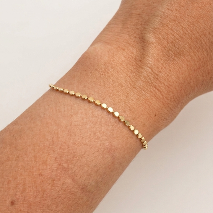 Gold filled  dotted chain bracelet on a wrist against a light background