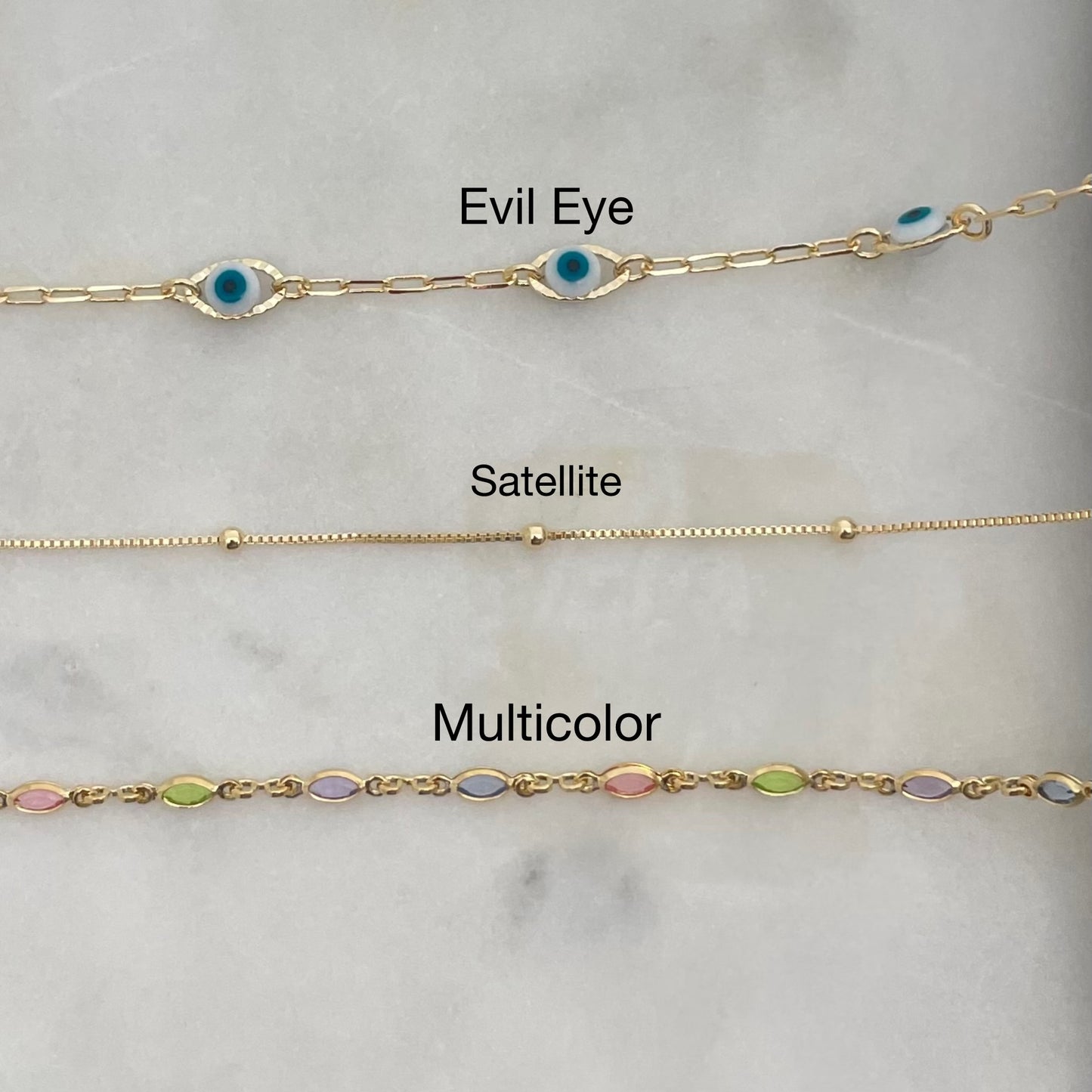 Top view of 3 anklets in gold filled over white stone display 