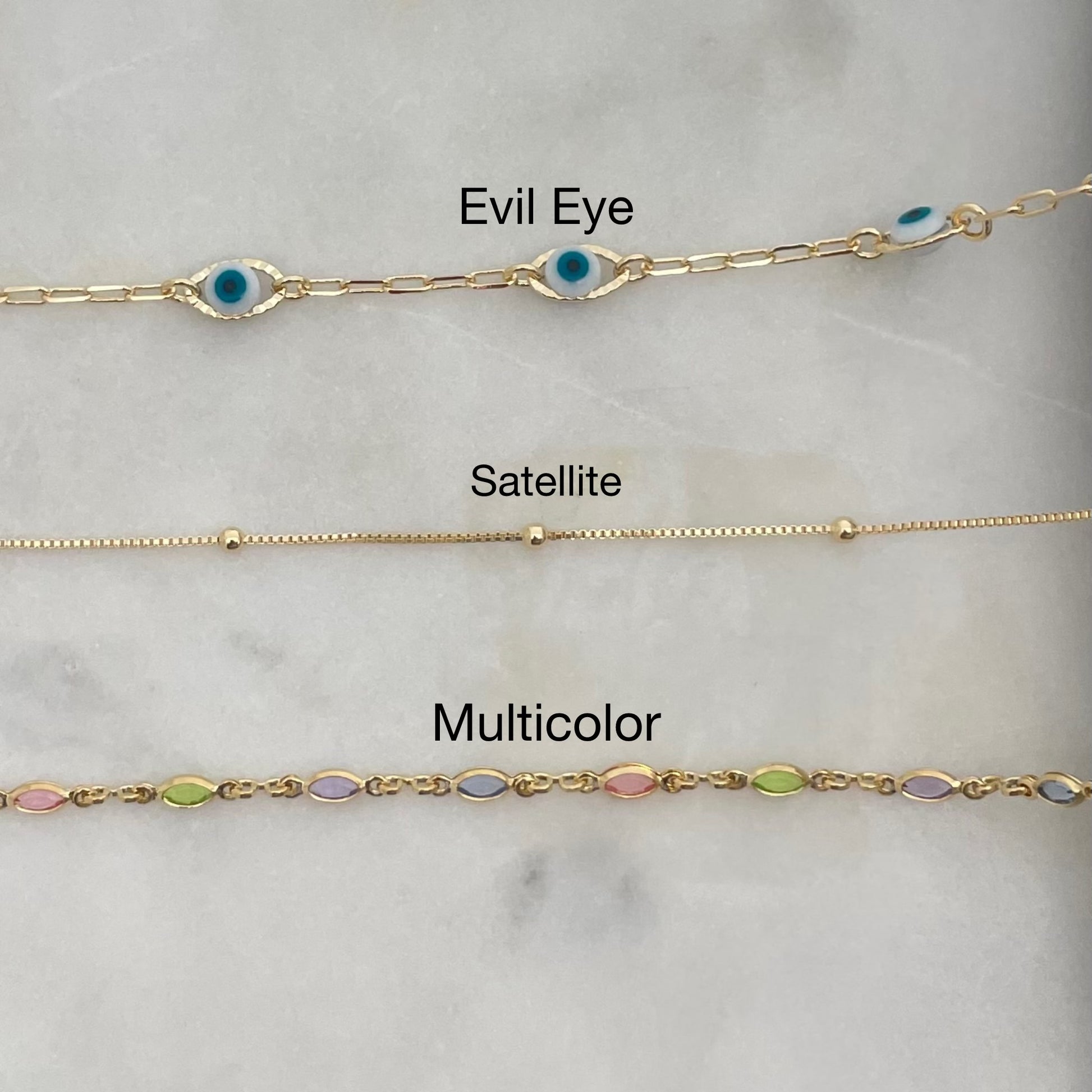 Top view of 3 anklets in gold filled over white stone display 