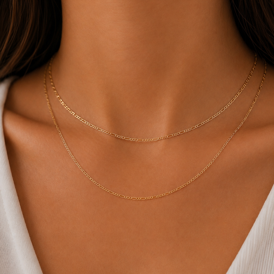 Close-up of a person wearing a delicate gold necklace against a neutral background