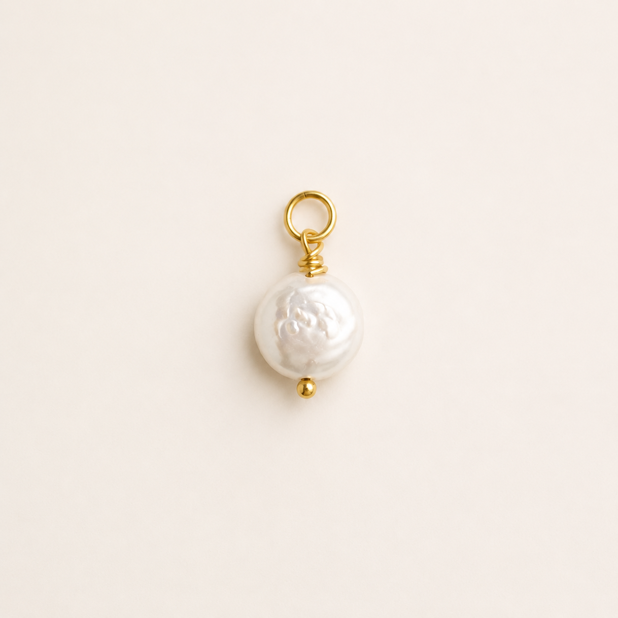 Flat Pearl charm with gold clasp on a light beige background