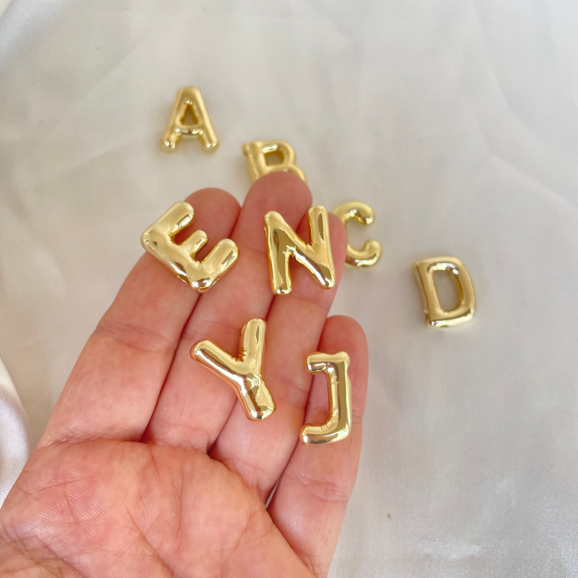 Gold Plated Initial Pendant hold on hand , white background