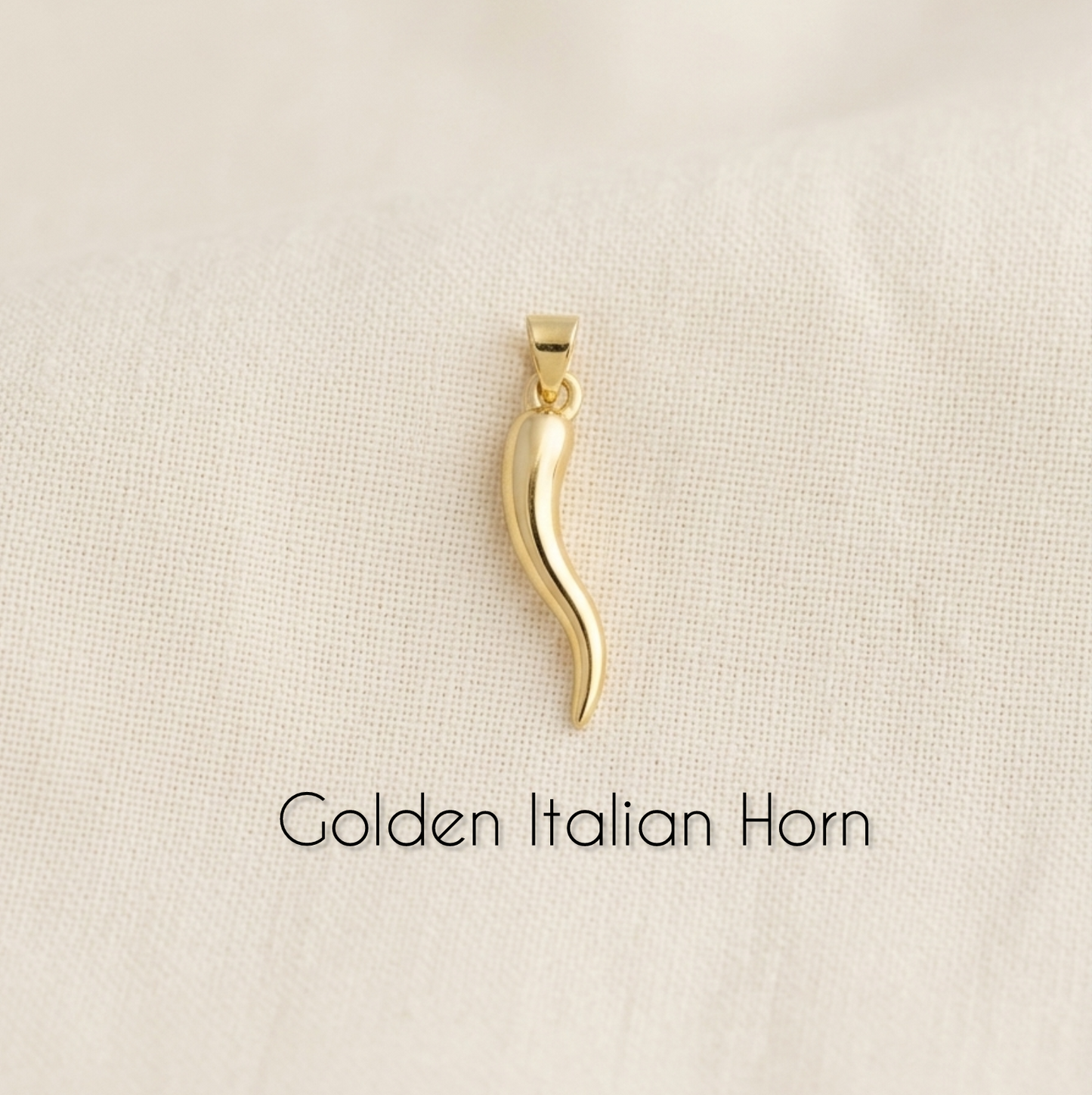Gold Italian horn pendant on a beige background