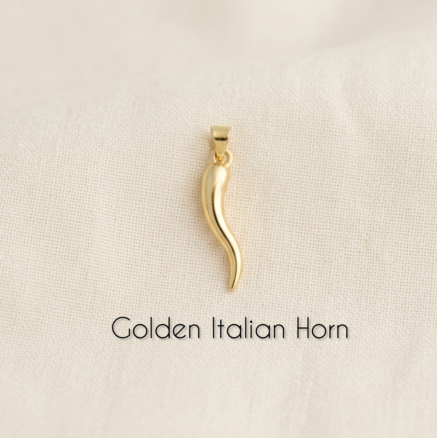 Gold Italian horn pendant on a beige background