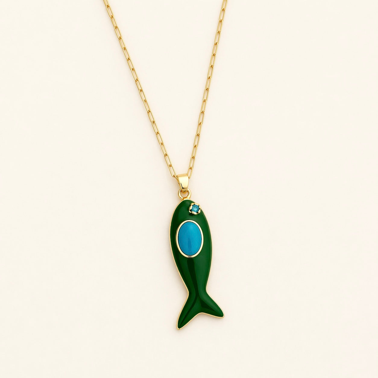 Green fish-shaped pendant with turquoise accent on a gold chain against a white background