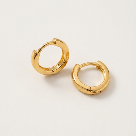 A pair of polished gold huggie hoop earrings on a clean, light off-white background.