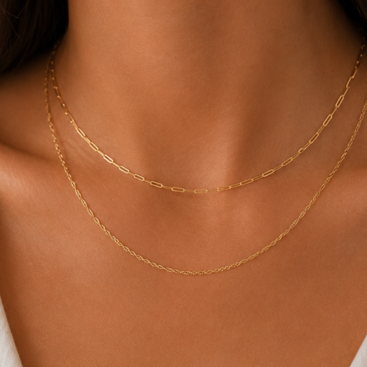 Close-up of a person wearing a gold necklace with a white top.