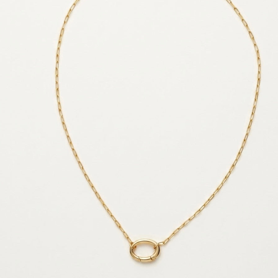 Gold necklace with a small round pendant on a light gray background