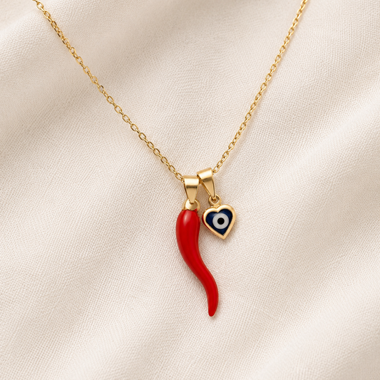 Gold filled necklace with a red italian horn and blue evil eye pendants on a beige fabric background
