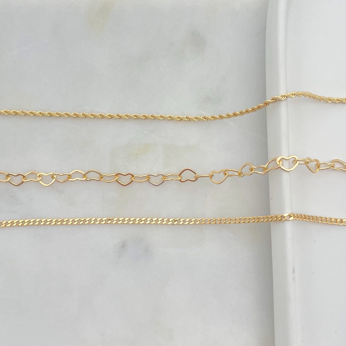Upper view of set of anklets in gold filled, white background