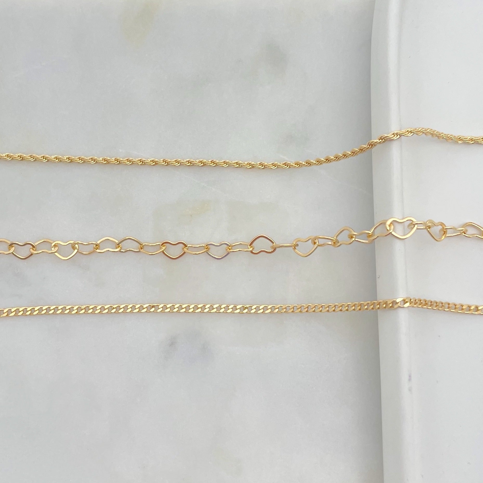 Upper view of set of anklets in gold filled, white background