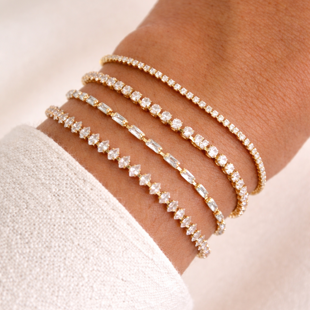 Close-up of a wrist with multiple gold bracelets on a light background