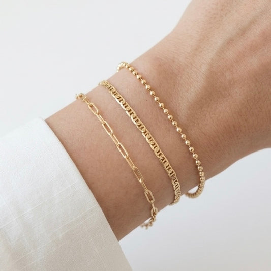 Gold bracelets on a wrist against a white background