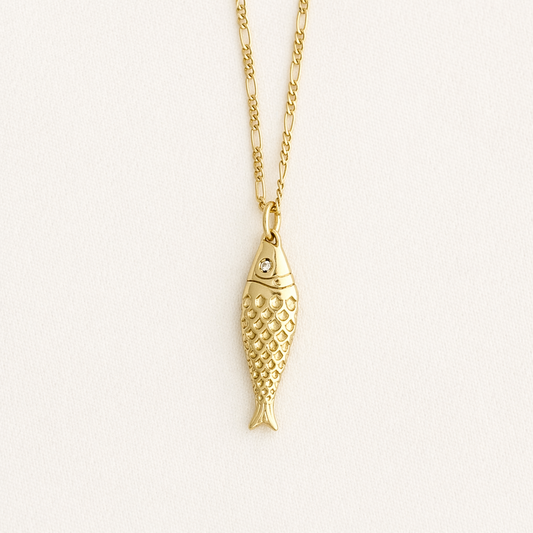 Gold fish-shaped pendant necklace on a light beige background