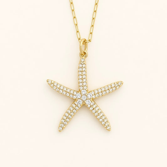 Close up of cubic zirconia starfish pendant on a gold chain a white background