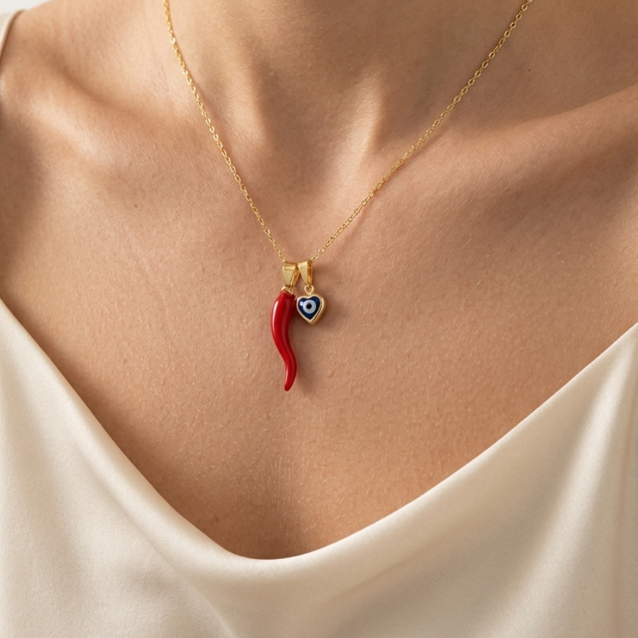 Gold filled figaro necklace with a red and blue pendant worn by a person in a white top.