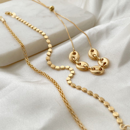 Bracelets displayed on marble tray and white silk, made of gold filled, 3 styles puffed link adjustable bracelet, dot bracelet, tube bracelet