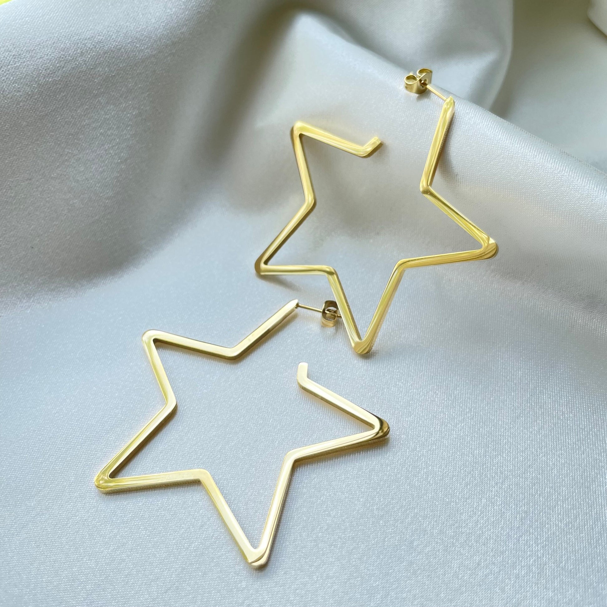 Stainless steel star hoops, 2.5 inches wide, push back hoop earring. White white silky background