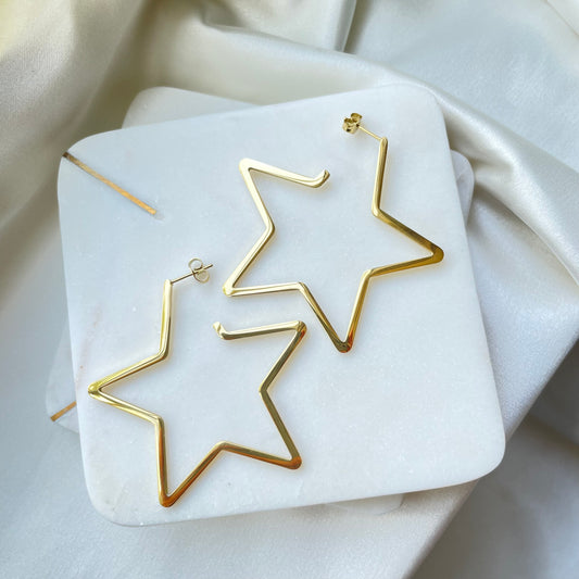 Stainless steel star hoops, 2.5 inches wide, push back hoop earring. Displayed on Marble tray and white silky background