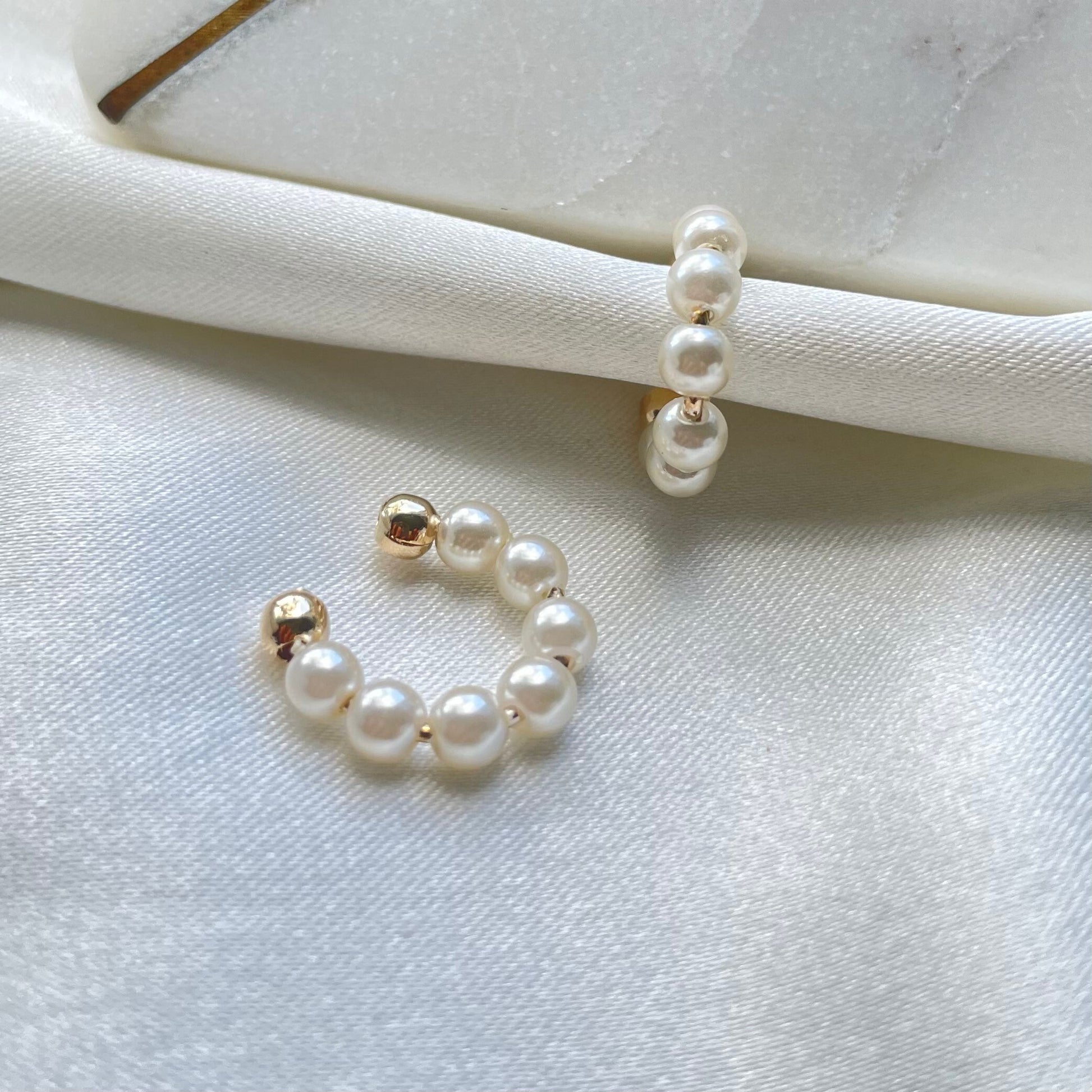 Faux pearl ear cuff with 18k gold filled beads at each end. White silk background