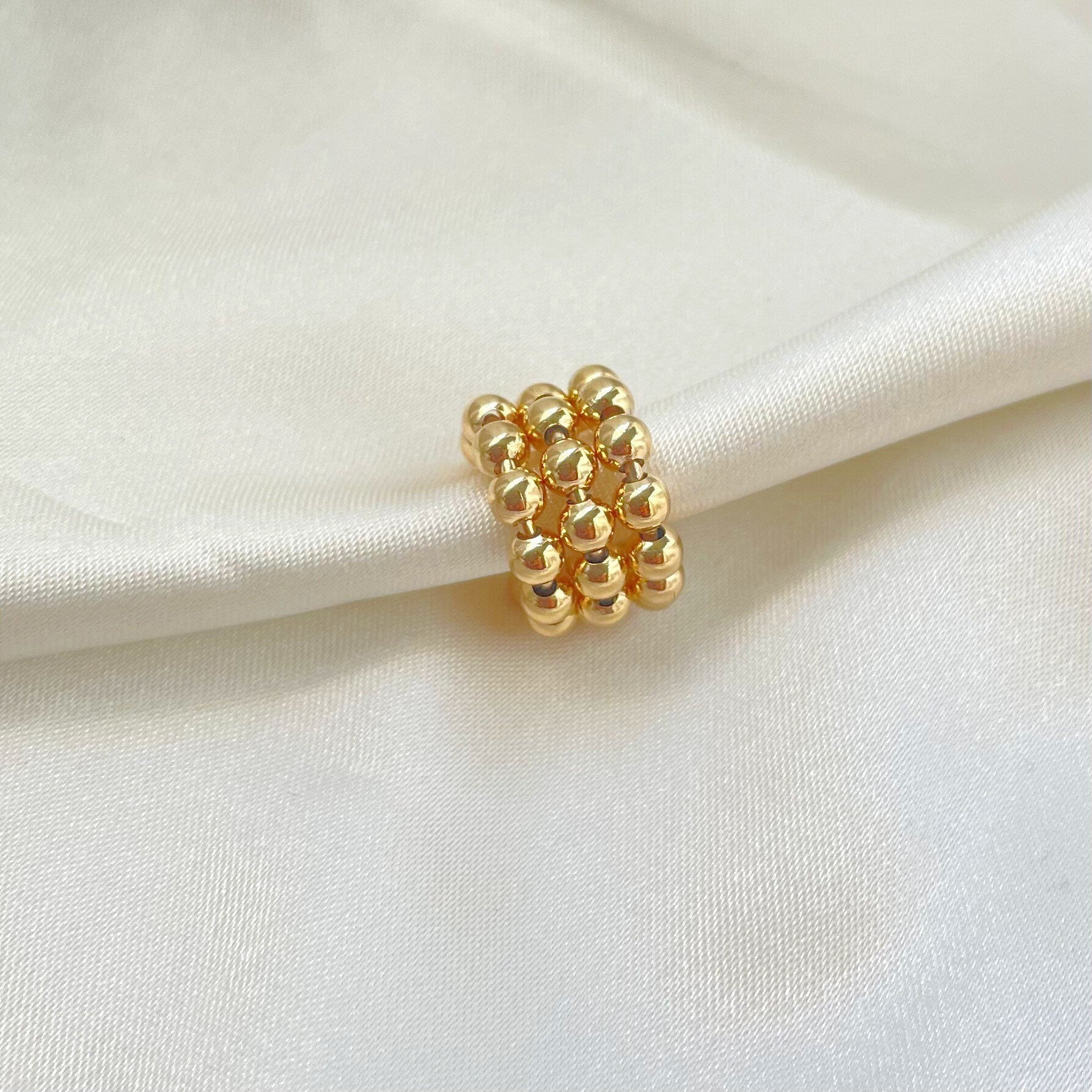 Triple band gold beaded ear cuff, material 18k gold filled, hypoallergenic and waterproof, white silk background