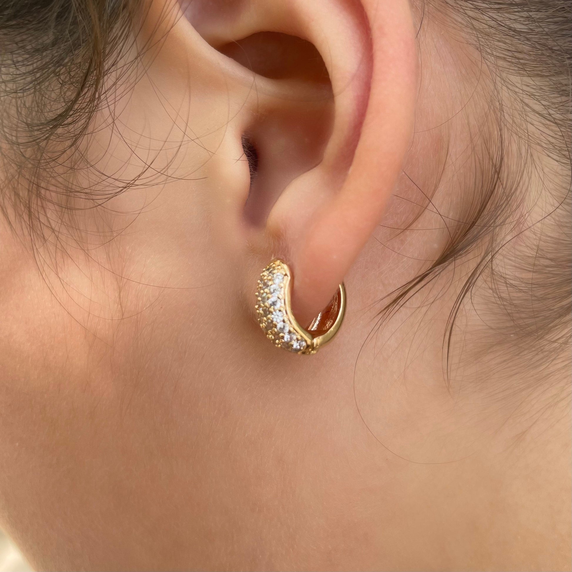 Side view of Cz chunky huggie hoop earrings in 18k gold filled. Wore by model. 