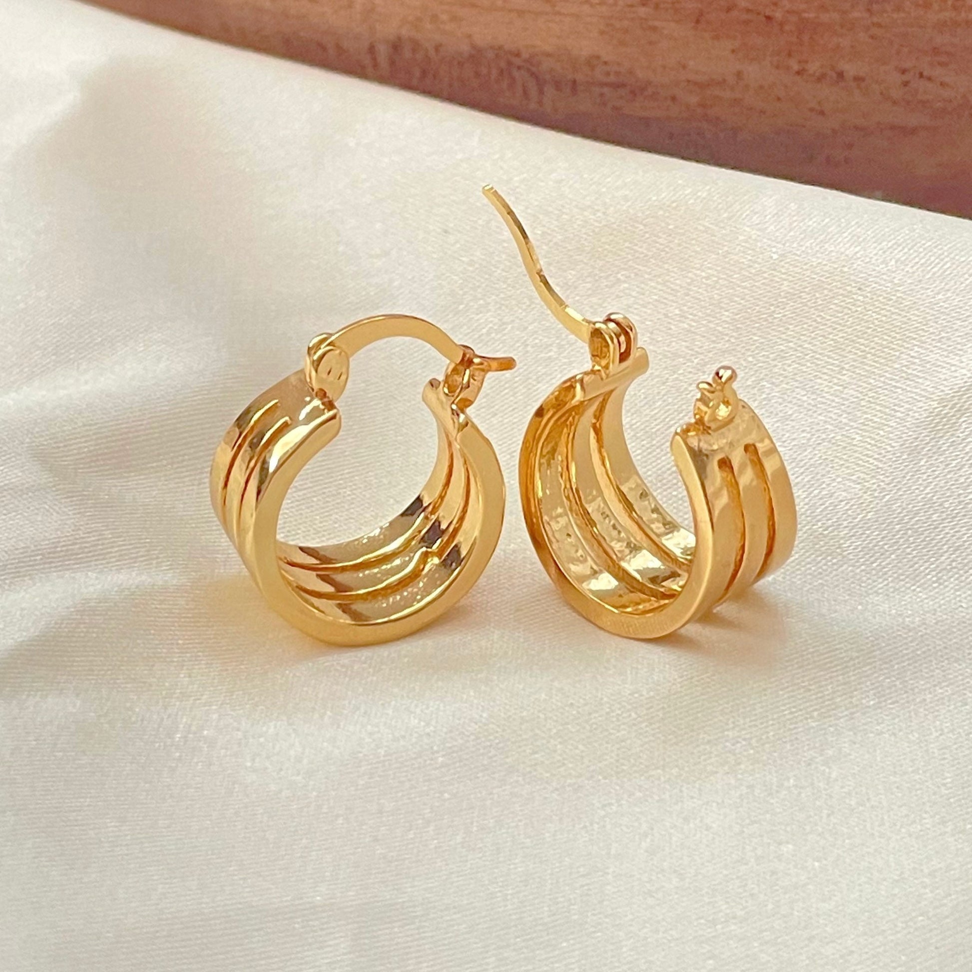 Closer look to Triple hoop earrings made in 18k gold filled, latch back hoop displayed on white silky fabric and wood tray decor.