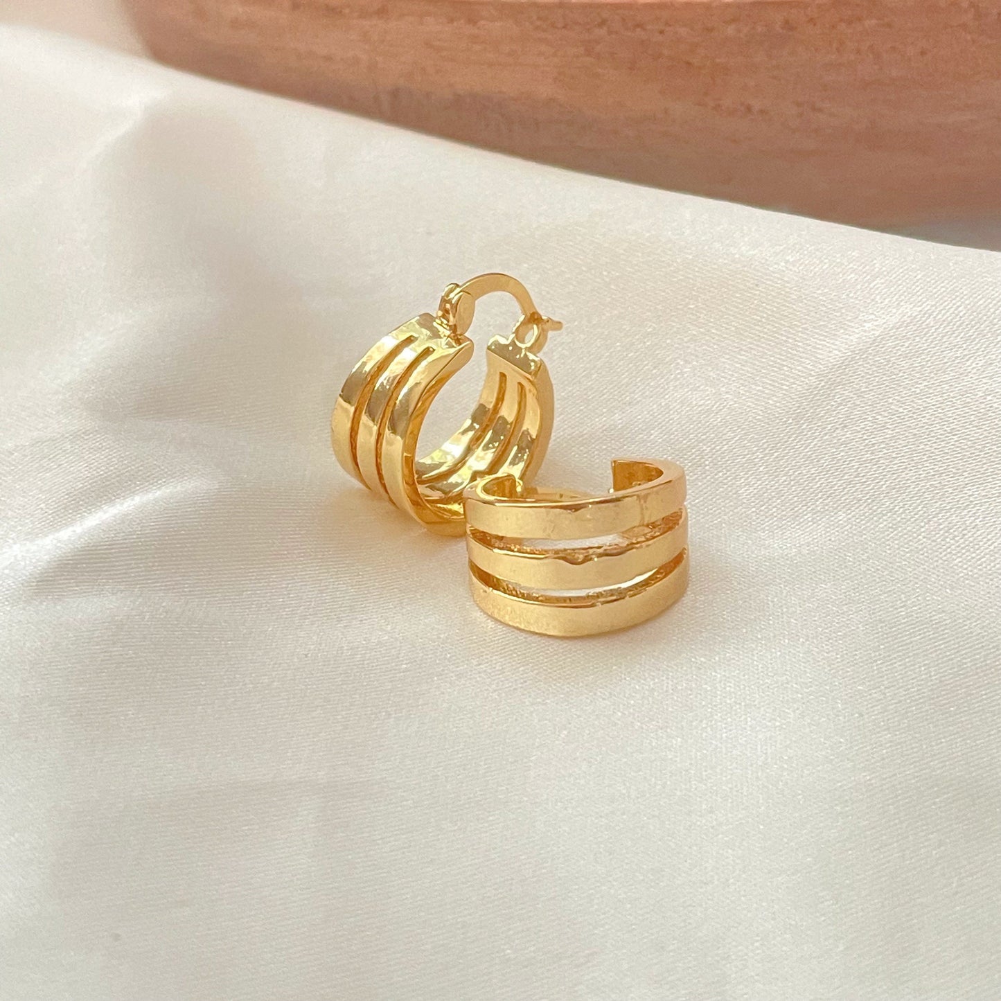 Triple hoop earrings made in 18k gold filled, latch back hoop displayed on white silky fabric and wood tray decor.