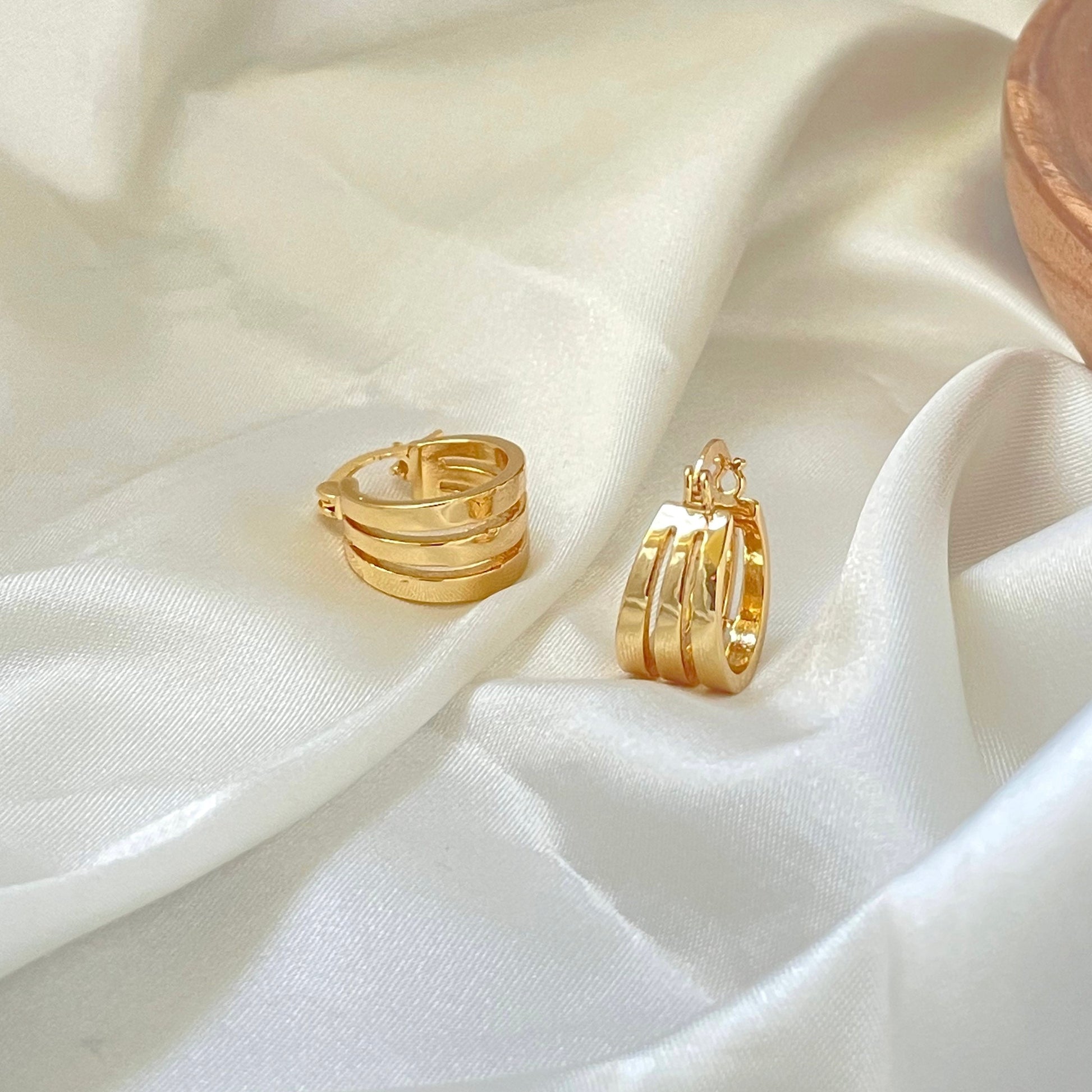 Triple hoop earrings made in 18k gold filled, latch back hoop displayed on white silky fabric