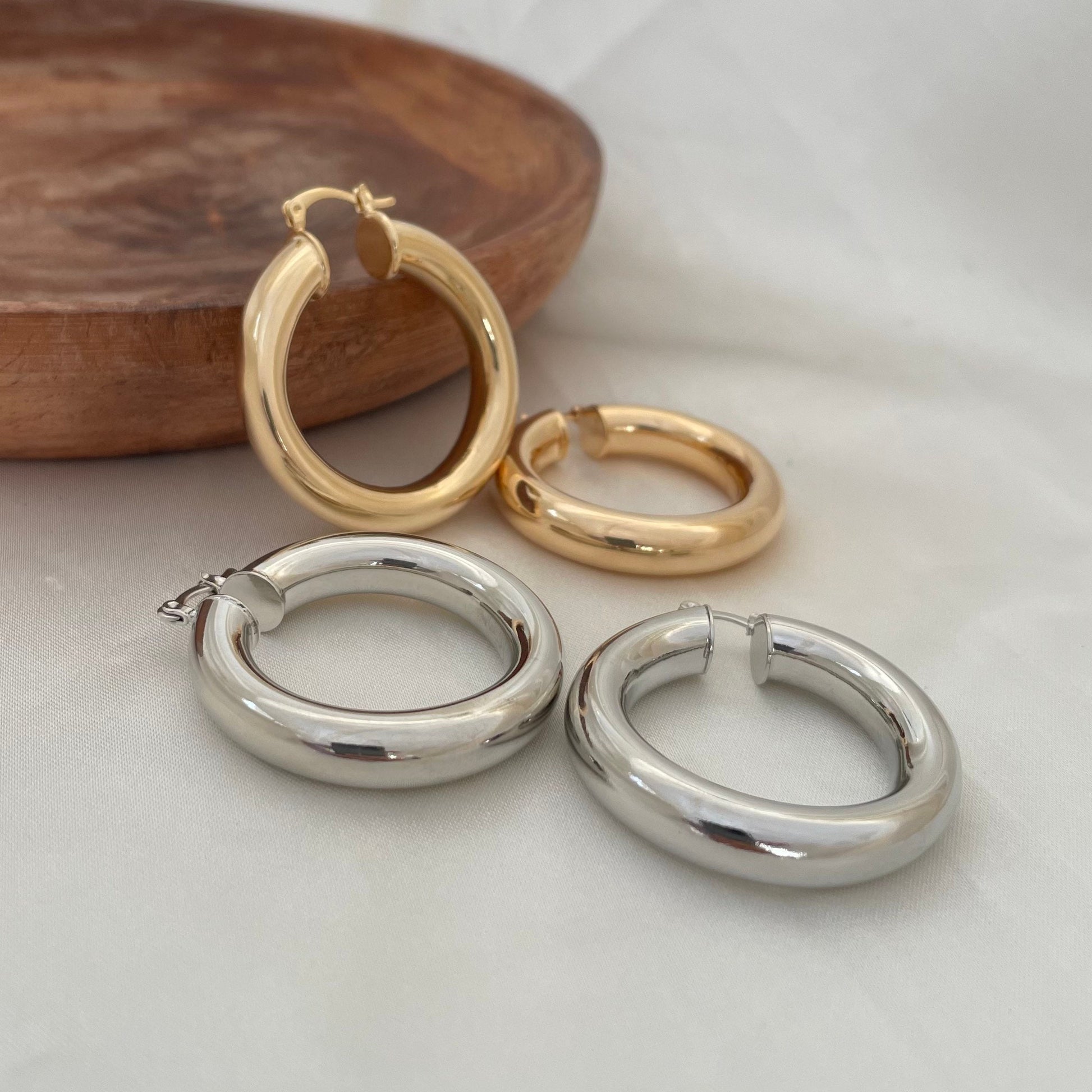 Chunky 18k gold filled and rhodium filled hoop earrings, 6 mm thick and 1.7 inches diameter. Latch back closure. White silk background and wood tray as decor