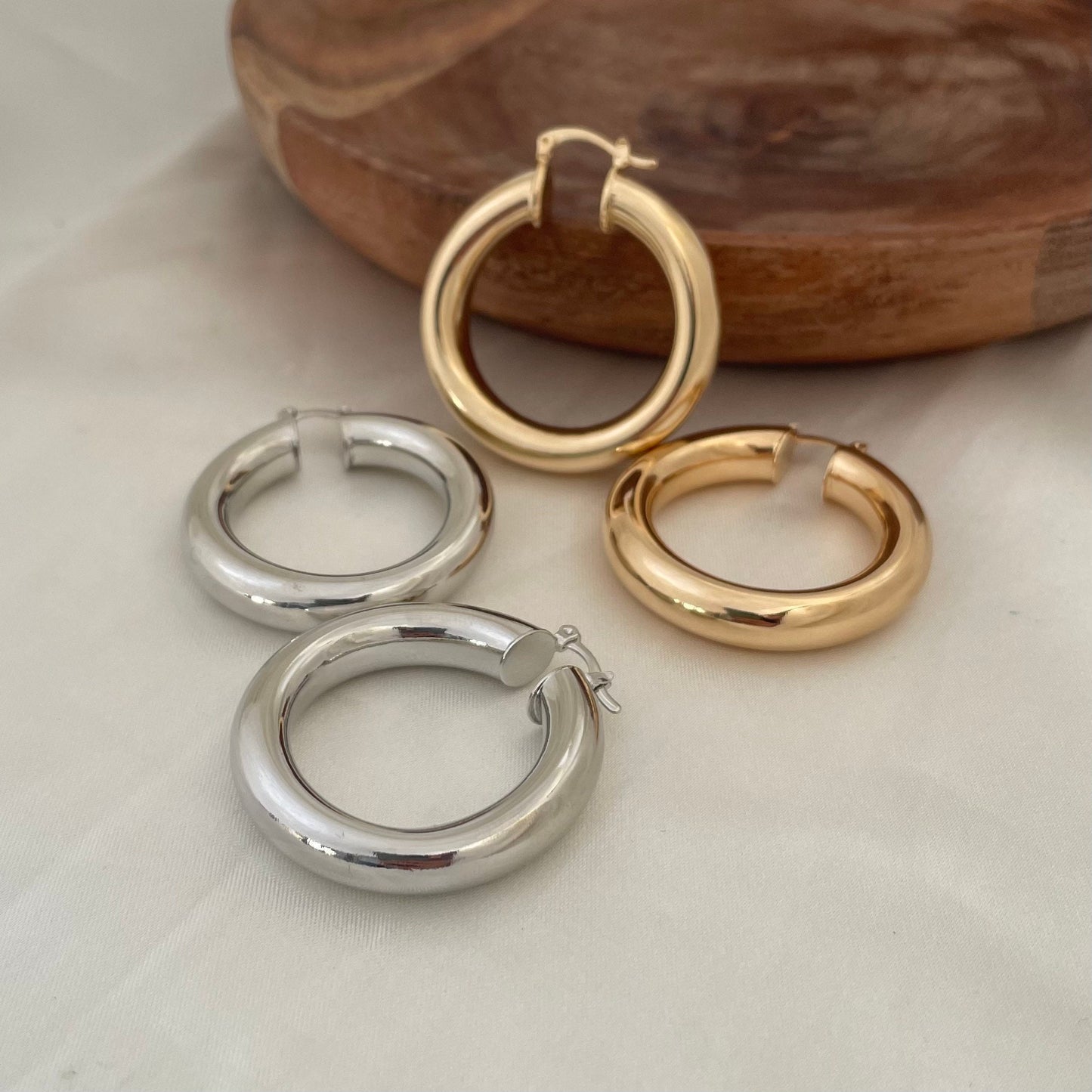 Chunky 18k gold filled  and rhodium filled (silver) hoop earrings, 6 mm thick and 1.7 inches diameter. Latch back closure. White silk background and wood tray as decor