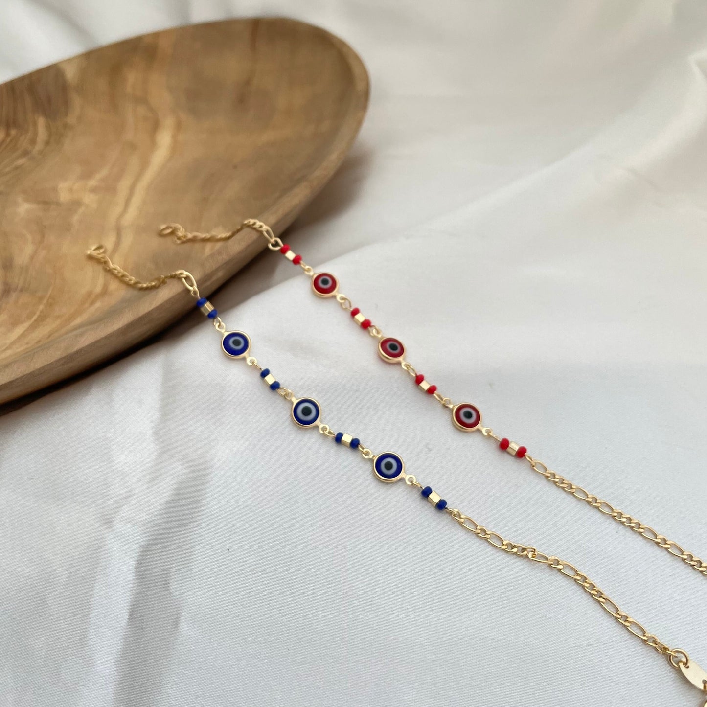 Royal blue and red evil eye bracelets made of 18k gold filled. White background 