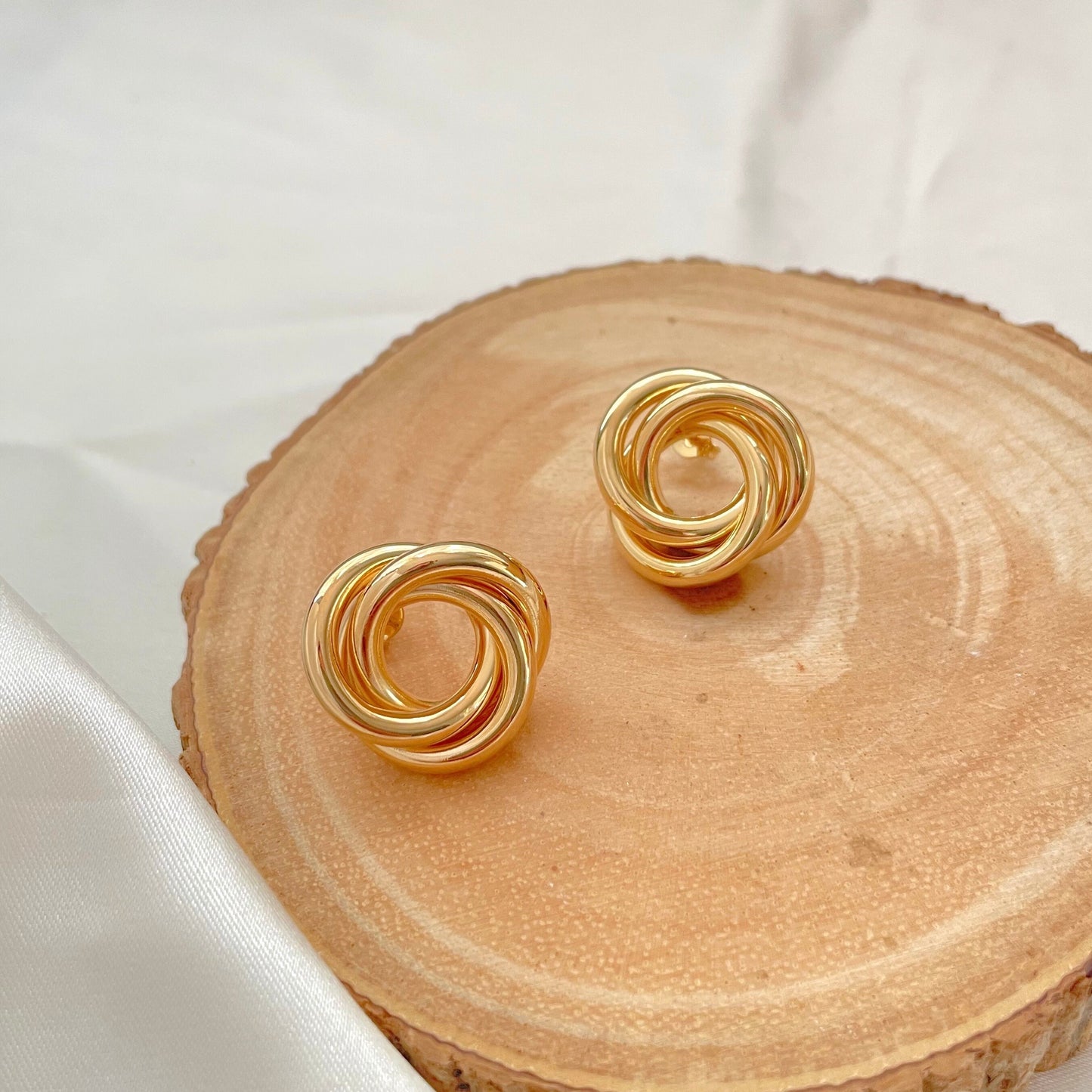 18k gold filled knot stud earrings, chunky and chubby knot earrings displayed on wood and white silk background 