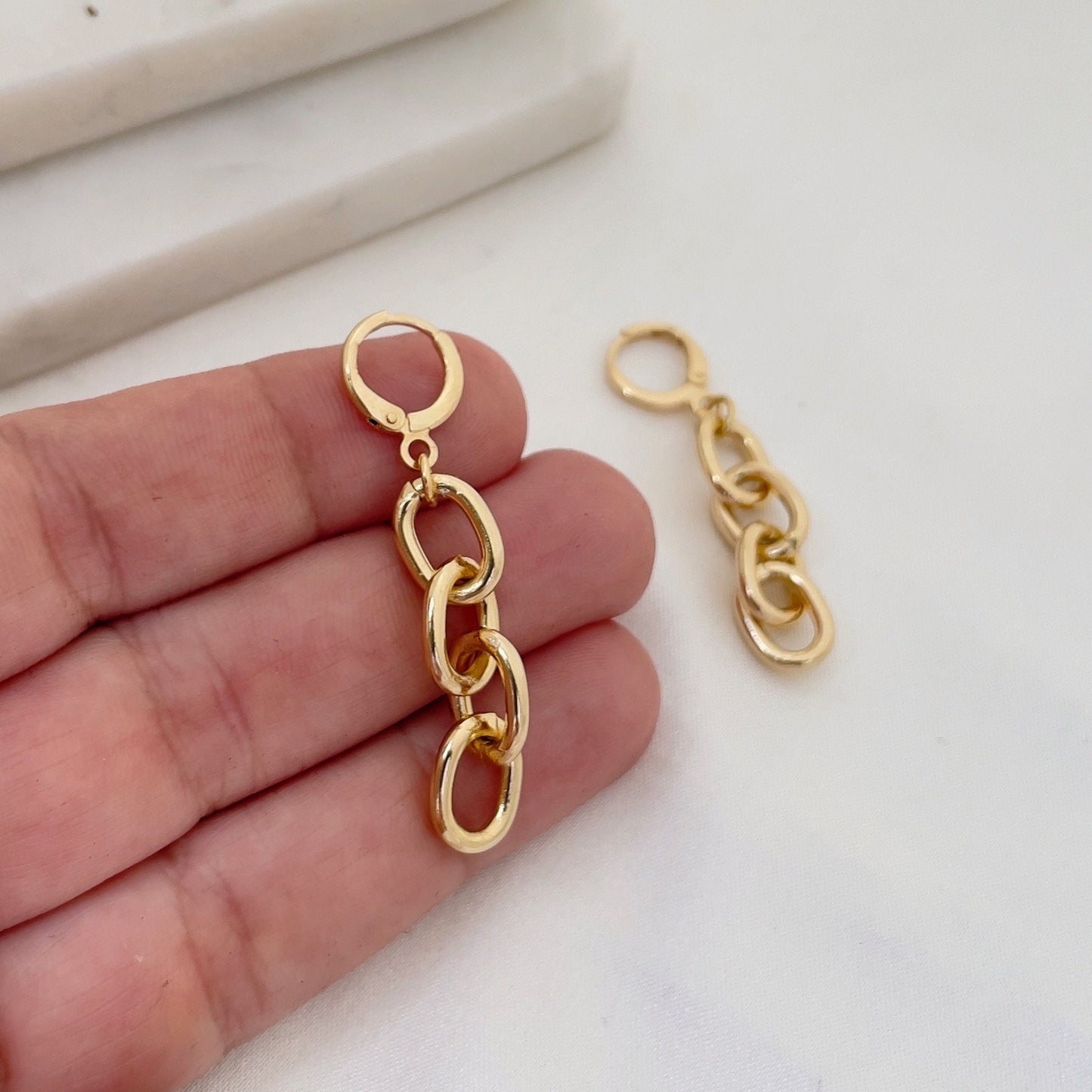 Chain hoop earrings made of 18k gold filled, hold in hand to appreciate length. White silk and marble background