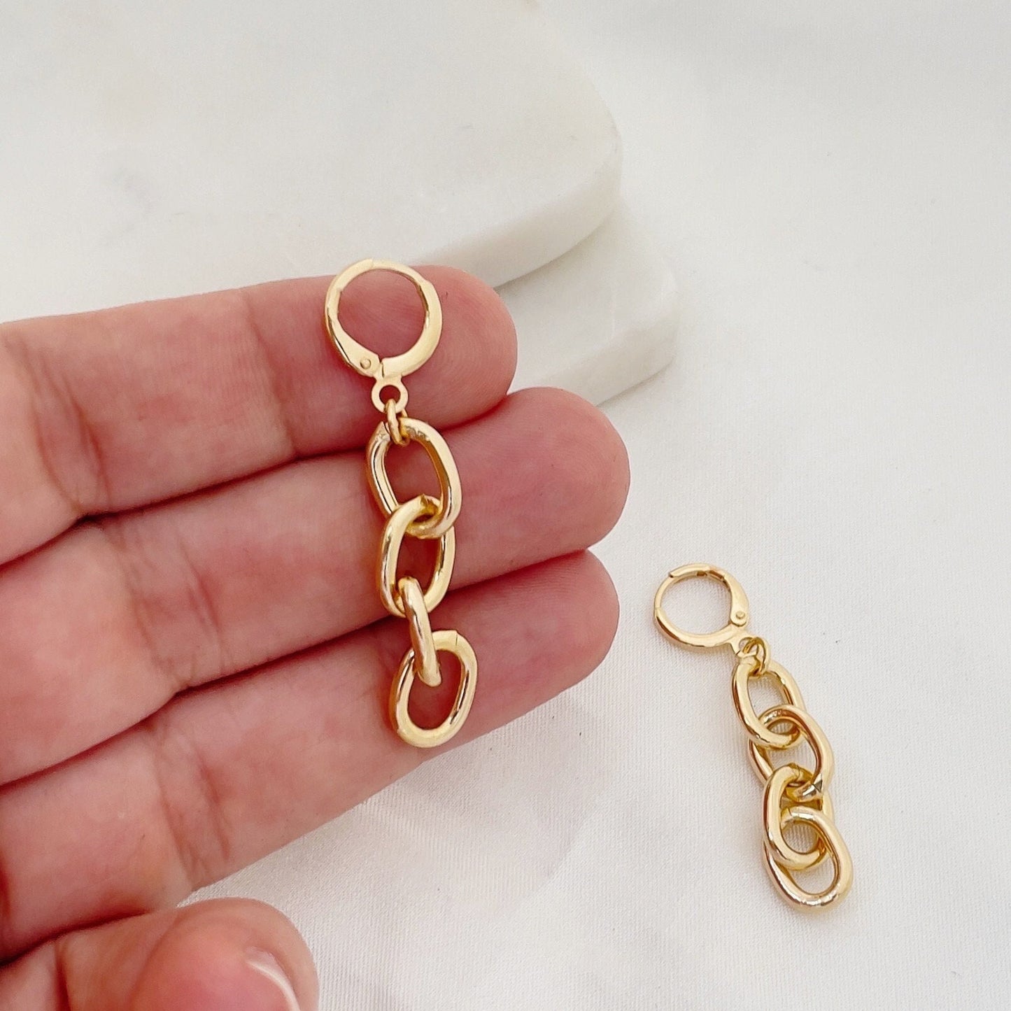 Chain hoop earrings made of 18k gold filled, hold in hand to appreciate length. White silk and marble background