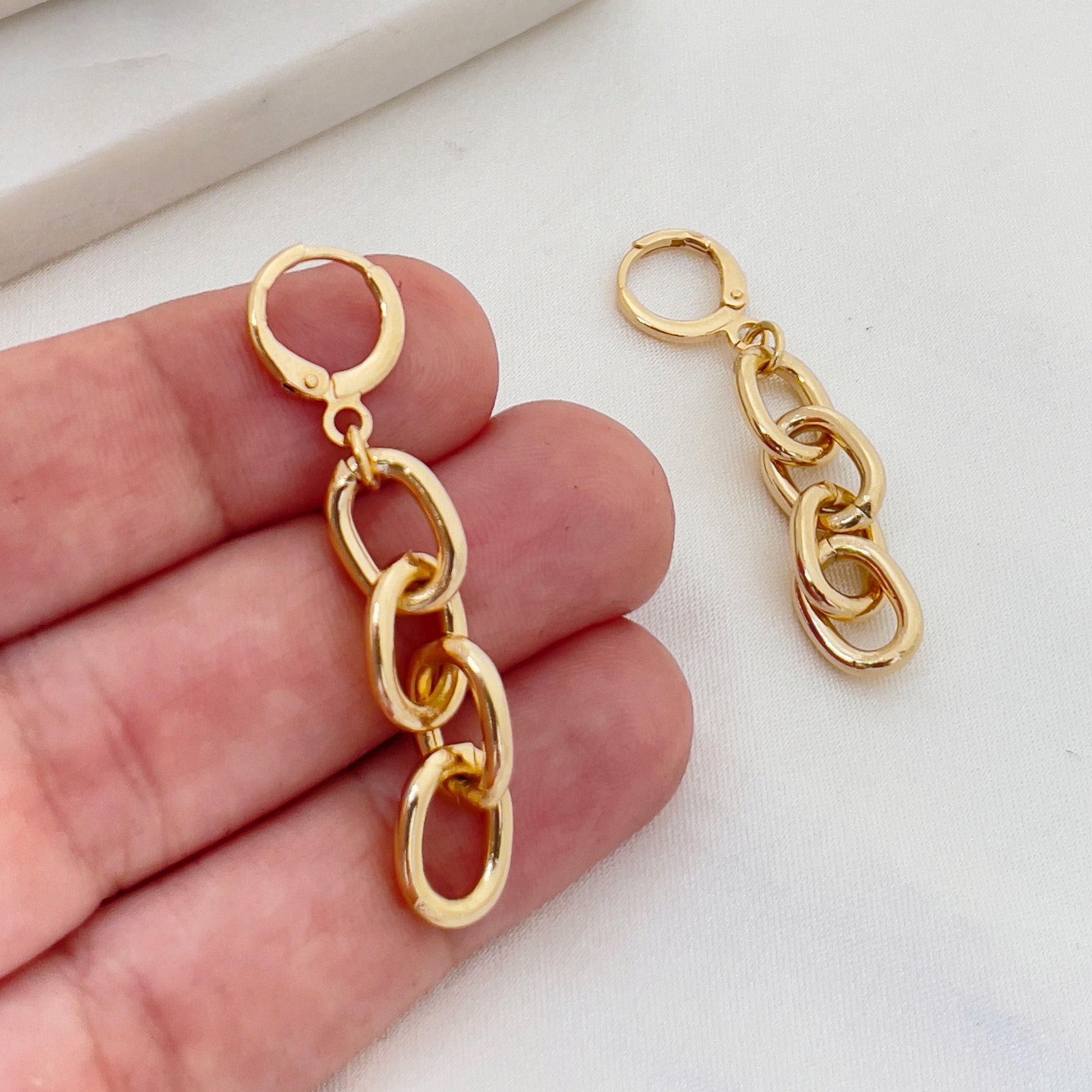 Chain hoop earrings made of 18k gold filled, hold in hand to appreciate length. White silk and marble background